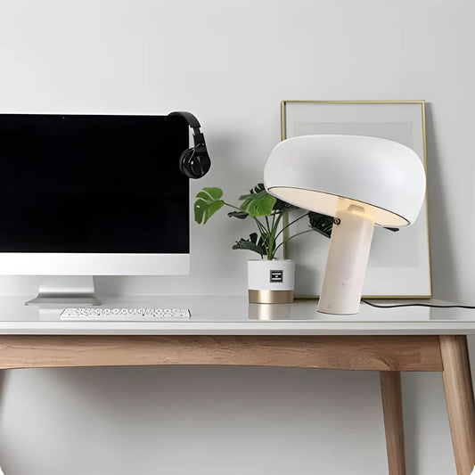 Minimalist desk setup with an iMac, headphones, plant, and mushroom-shaped lamp