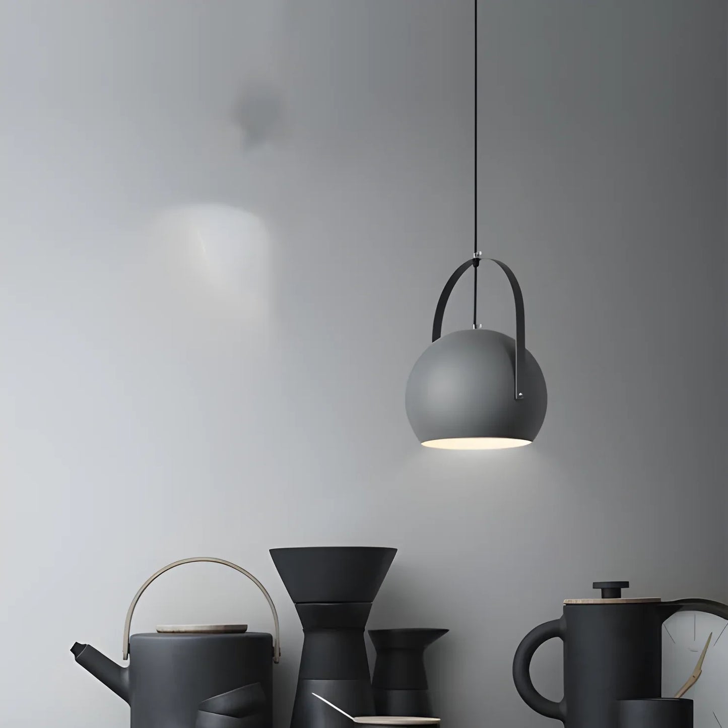 Matte black pendant light with a spherical shade and curved arm mount