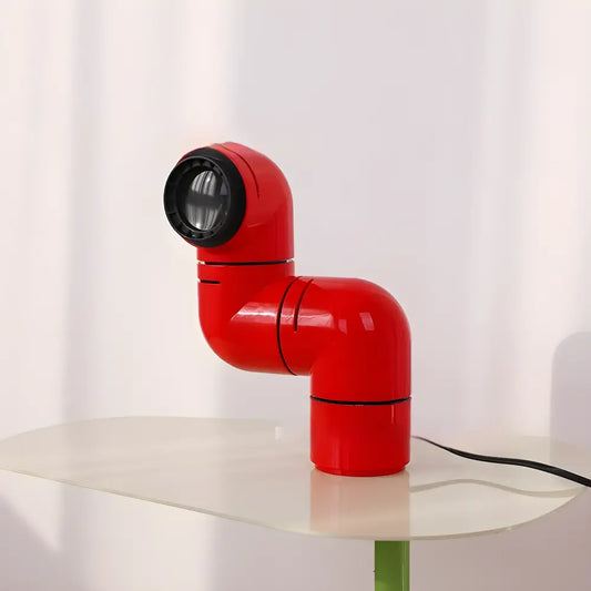 Red Space Age water pipe lamp with rotating design on a table, adding modern simplicity and bold style to any space.